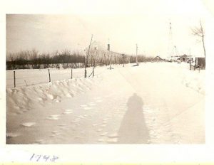 Haultain, Wetaskiwin farm home to the Humbke family of 12 plus windmill, building and car on a winter day in 1948.